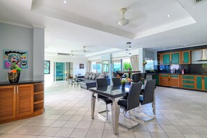 A spacious living area with a dining table, chairs, and a kitchen area with wooden cabinets. - Spacious 5BR Villa with Pool&Annex (JB1) (Pattaya)