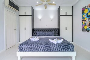 A bedroom with a bed, two wardrobes, a ceiling fan, and a wall-mounted light fixture. - Spacious 5BR Villa with Pool&Annex (JB1) (Pattaya)