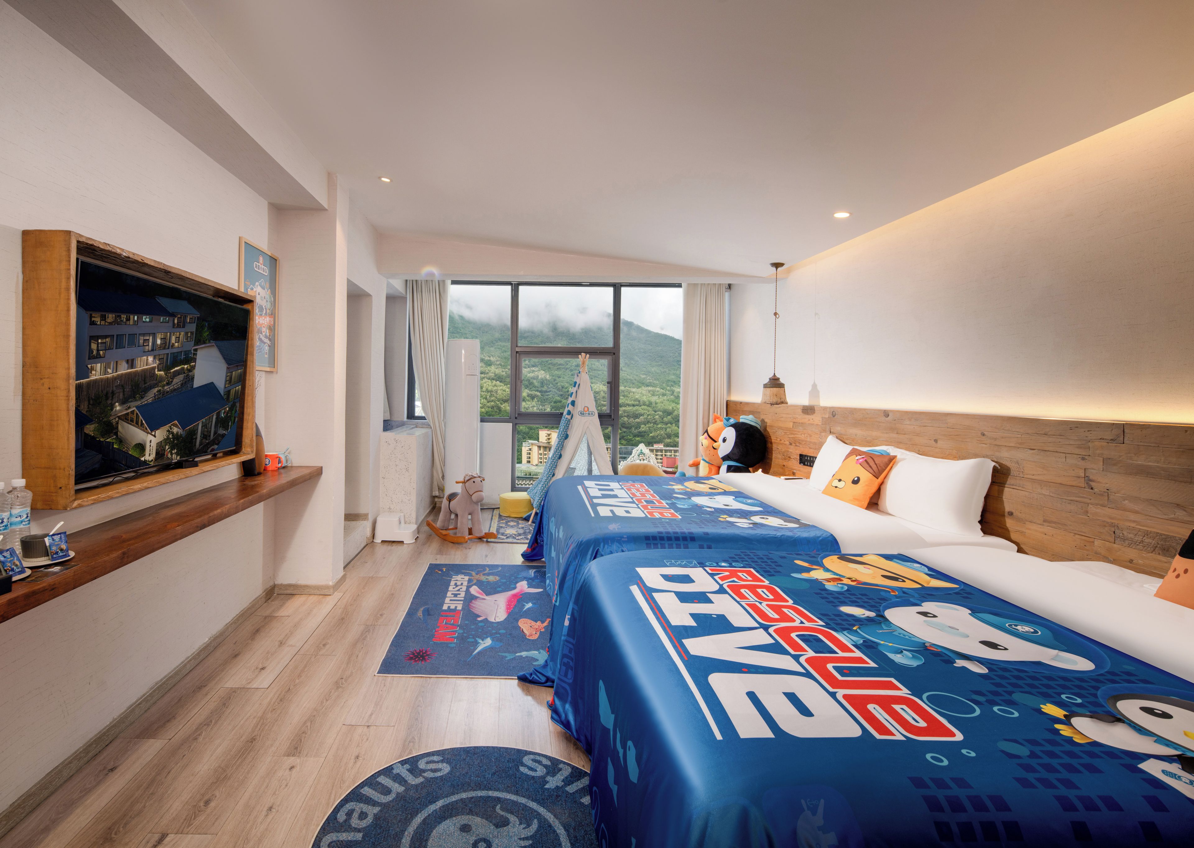 Habitación de hotel con una cama grande, un televisor en la pared y vistas a un paisaje montañoso.