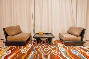 Una habitación con dos sillones, una mesita con una caja de pañuelos y una alfombra estampada.