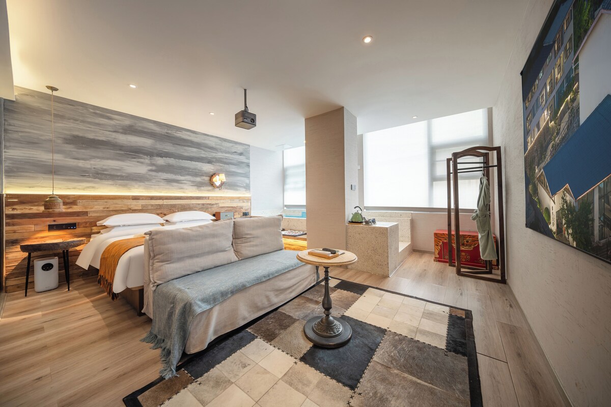 Une chambre d’hôtel moderne dotée d’un lit, d’un coin salon et offrant une vue sur la ville.