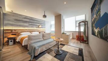 A modern hotel room with a bed, seating area, and a view of the city.