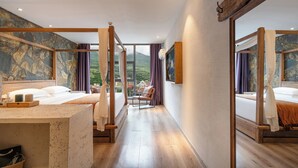 Ein Hotelzimmer mit einem großen Bett, einer Sitzecke und Blick auf eine Berglandschaft.