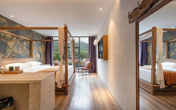 Habitación de hotel con una cama grande, zona de estar y vistas a un paisaje montañoso.
