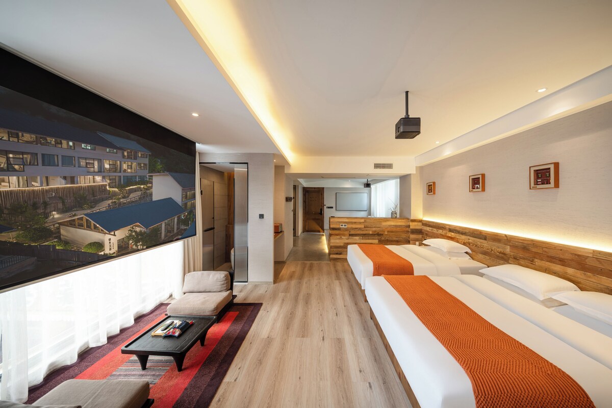Une chambre d’hôtel moderne dotée d’une grande fenêtre, d’un canapé, d’une table basse et d’un téléviseur.