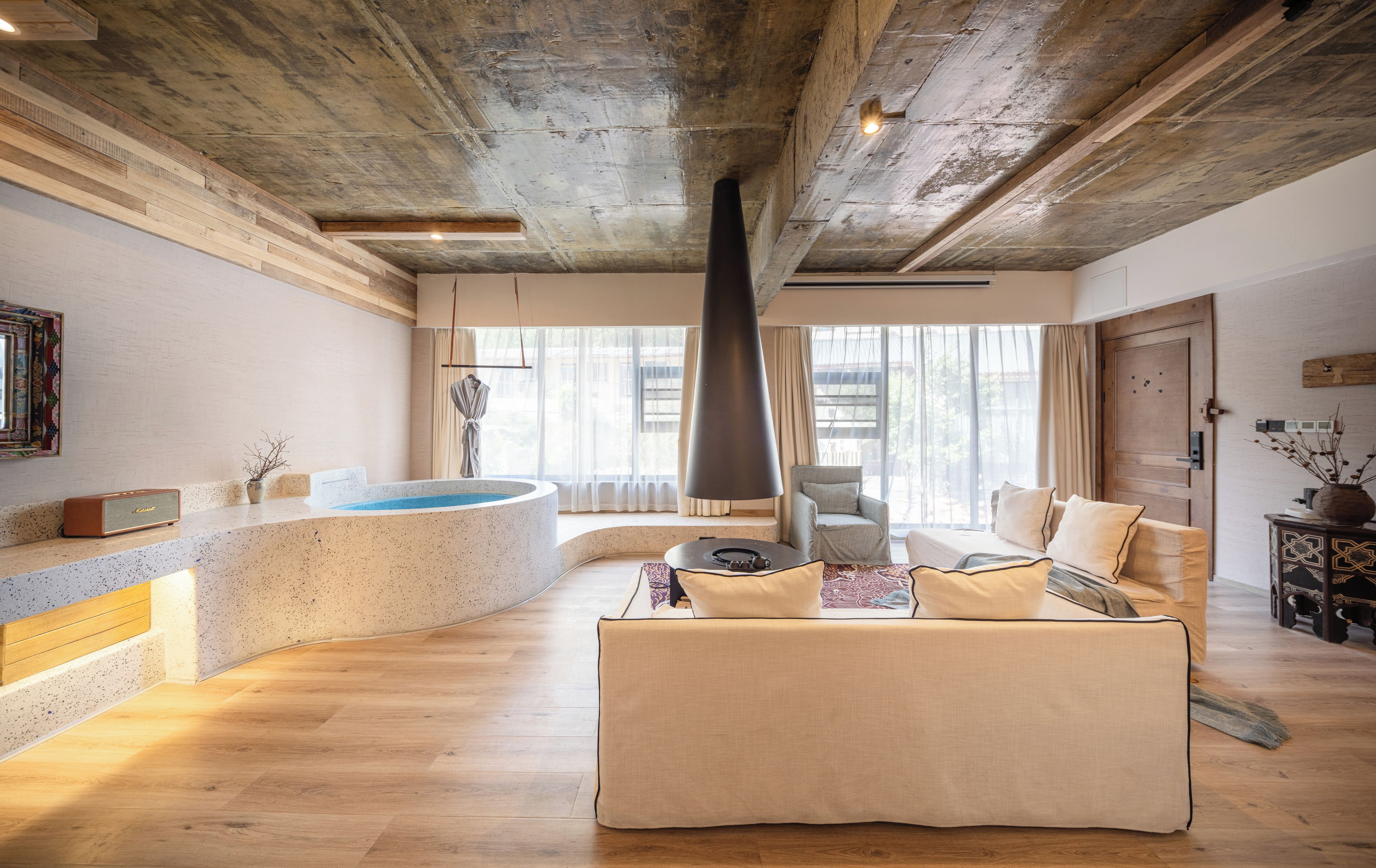 Una habitación amplia con zona de spa, un ventanal grande y una chimenea moderna.