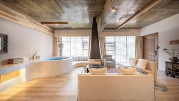 Una habitación amplia con zona de spa, un ventanal grande y una chimenea moderna.