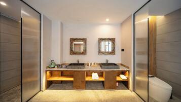 A modern bathroom with two sinks, wooden benches, and a toilet.