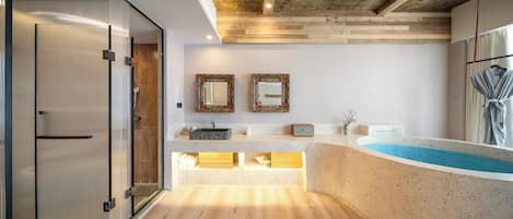 Un baño moderno con una bañera independiente, cabina de ducha con mampara de vidrio y tocador con lavamanos.