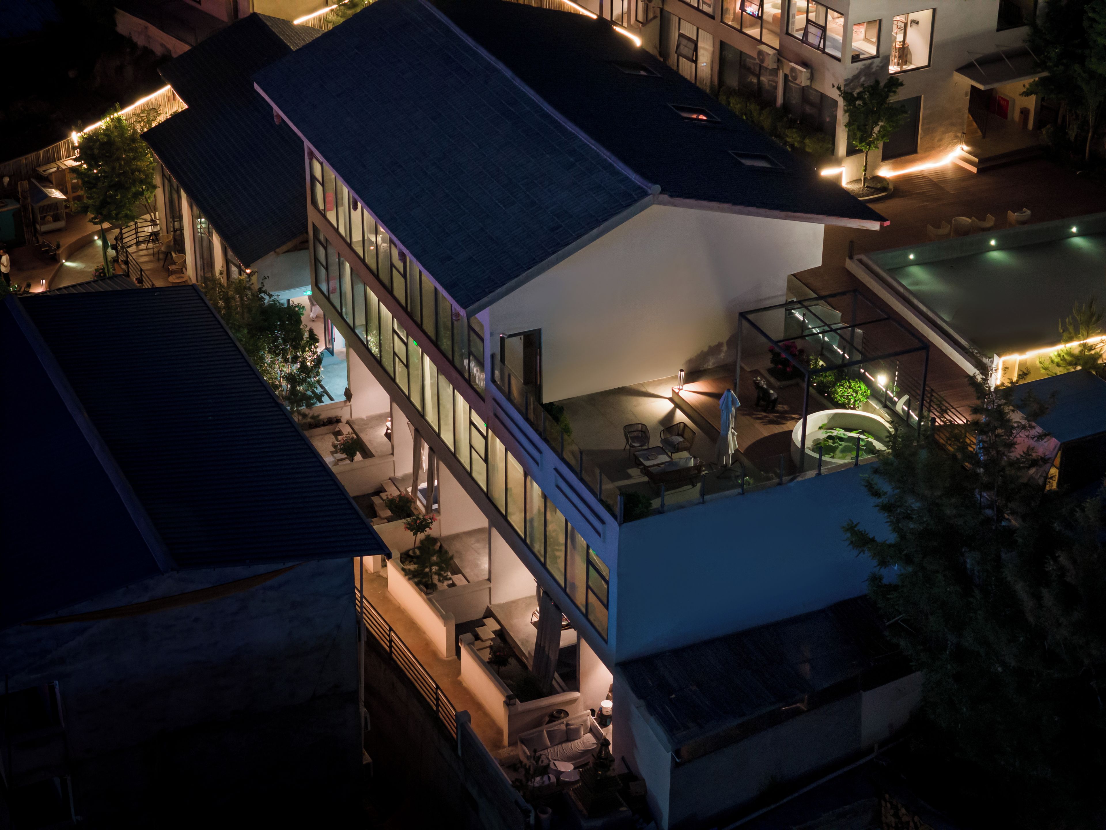 A multi-story building with a rooftop terrace, outdoor seating area, and a swimming pool.