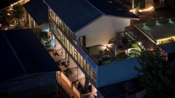 A multi-story building with a rooftop terrace, outdoor seating area, and a swimming pool.