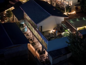 A multi-story building with a rooftop terrace, outdoor seating area, and a swimming pool.