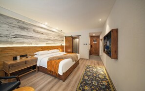 A modern hotel room with a wooden headboard, a large bed with white linens, a bedside table with a lamp, a wooden bench, and a patterned rug. - Yunfuli Jingshui Yunju Hotel (Ngawa Autonomous Prefecture)