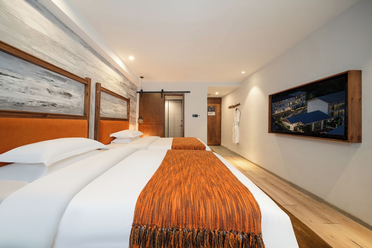 A hotel room with a large bed, a wooden headboard, a painting on the wall, and a view of the building outside.