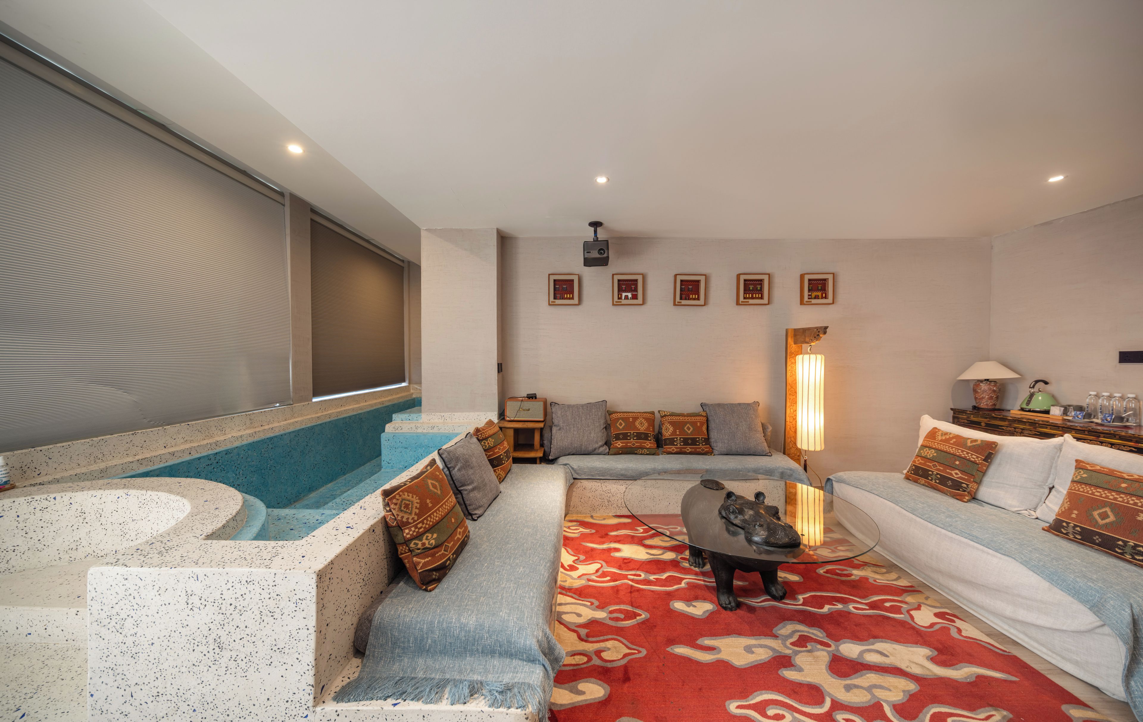 A modern living room with a spa tub, seating area, and a projector screen.