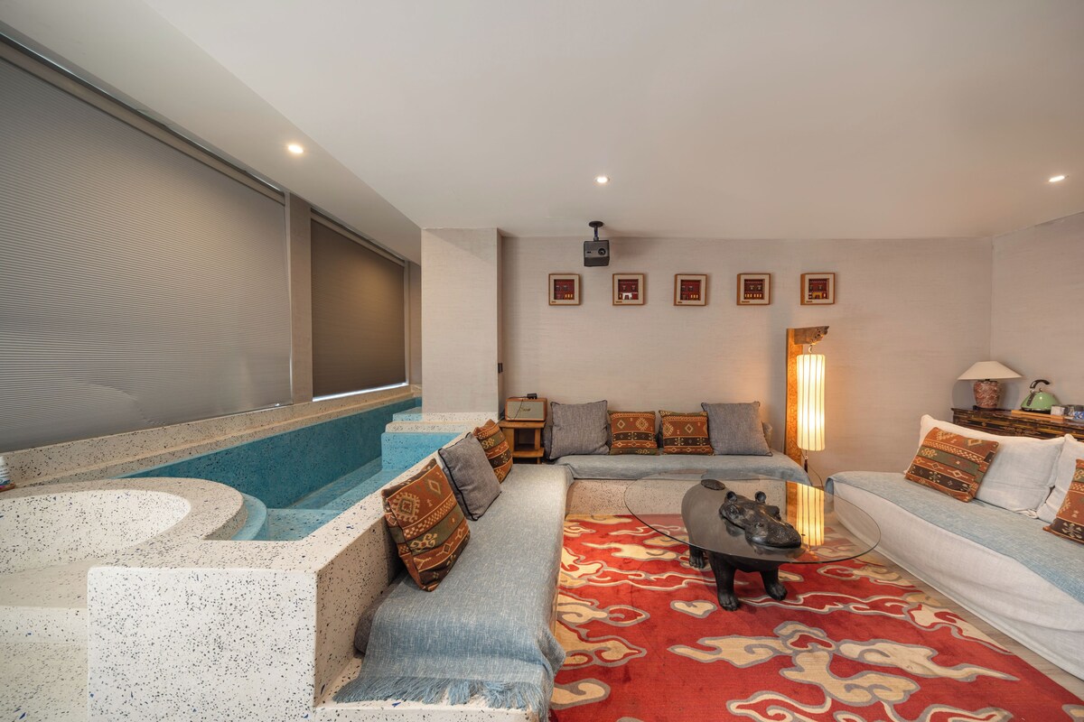A modern living room with a spa tub, seating area, and a projector screen.