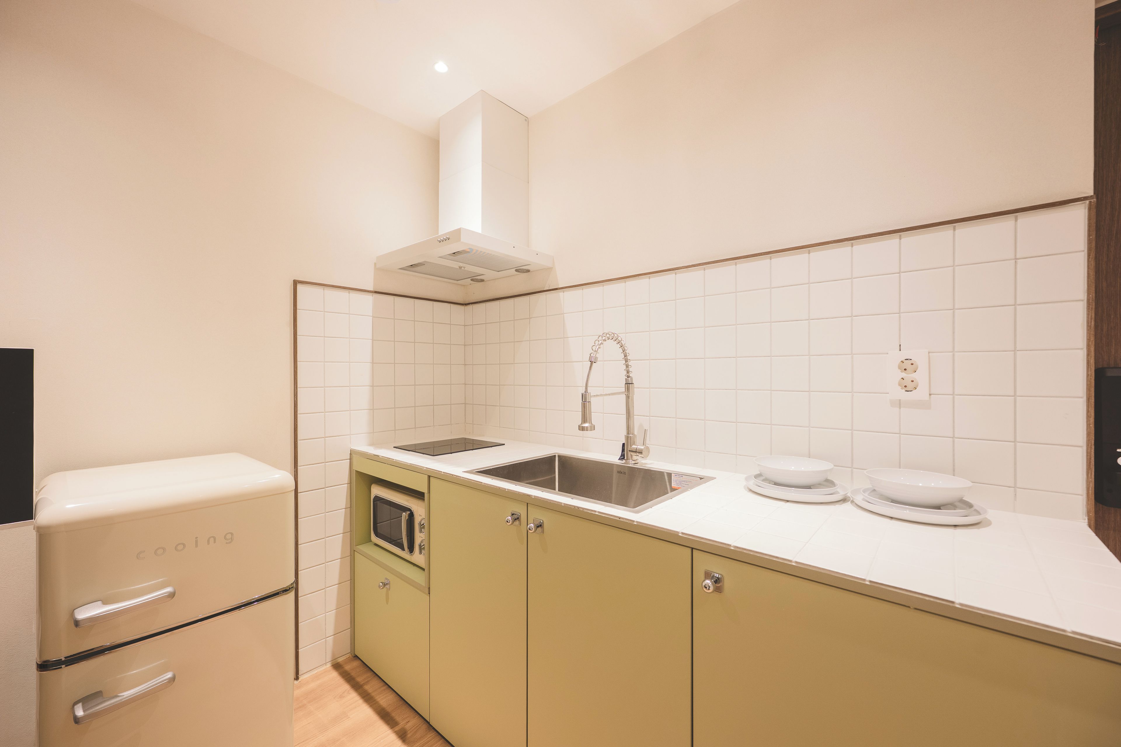 A compact kitchen with a built-in microwave, a stainless steel sink, and a compact refrigerator.