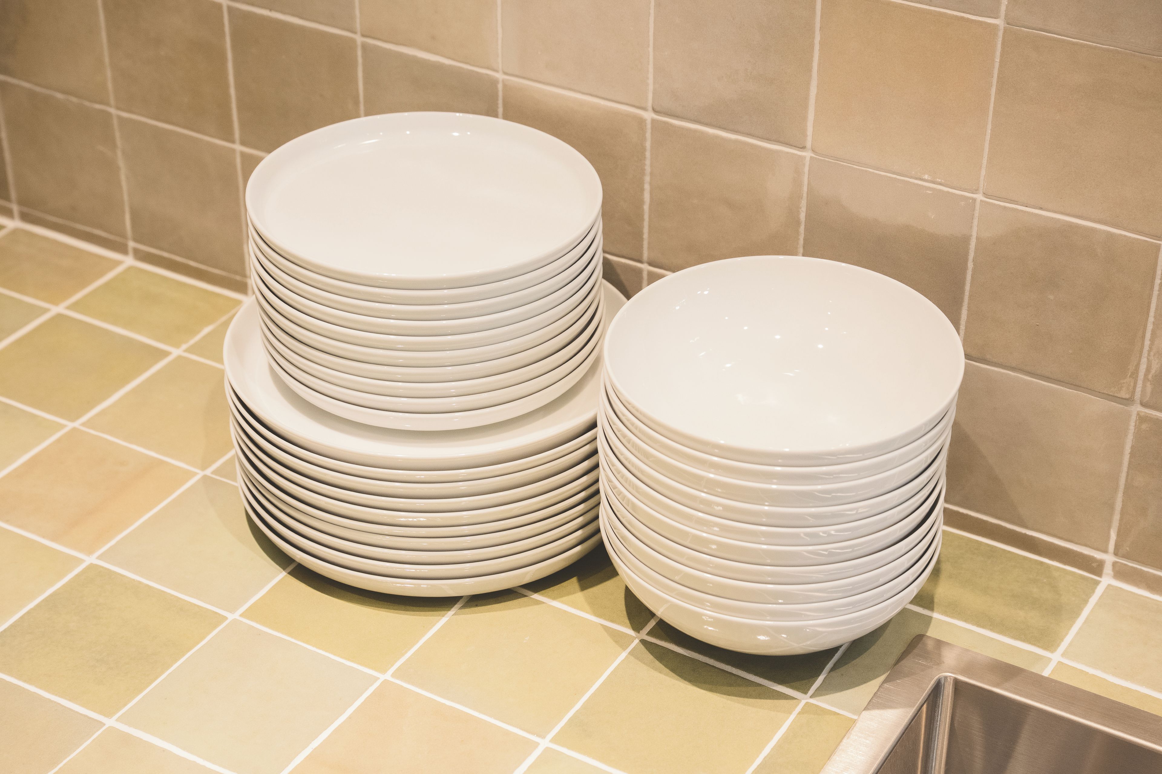 Una pila de platos blancos sobre una superficie con baldosas.
