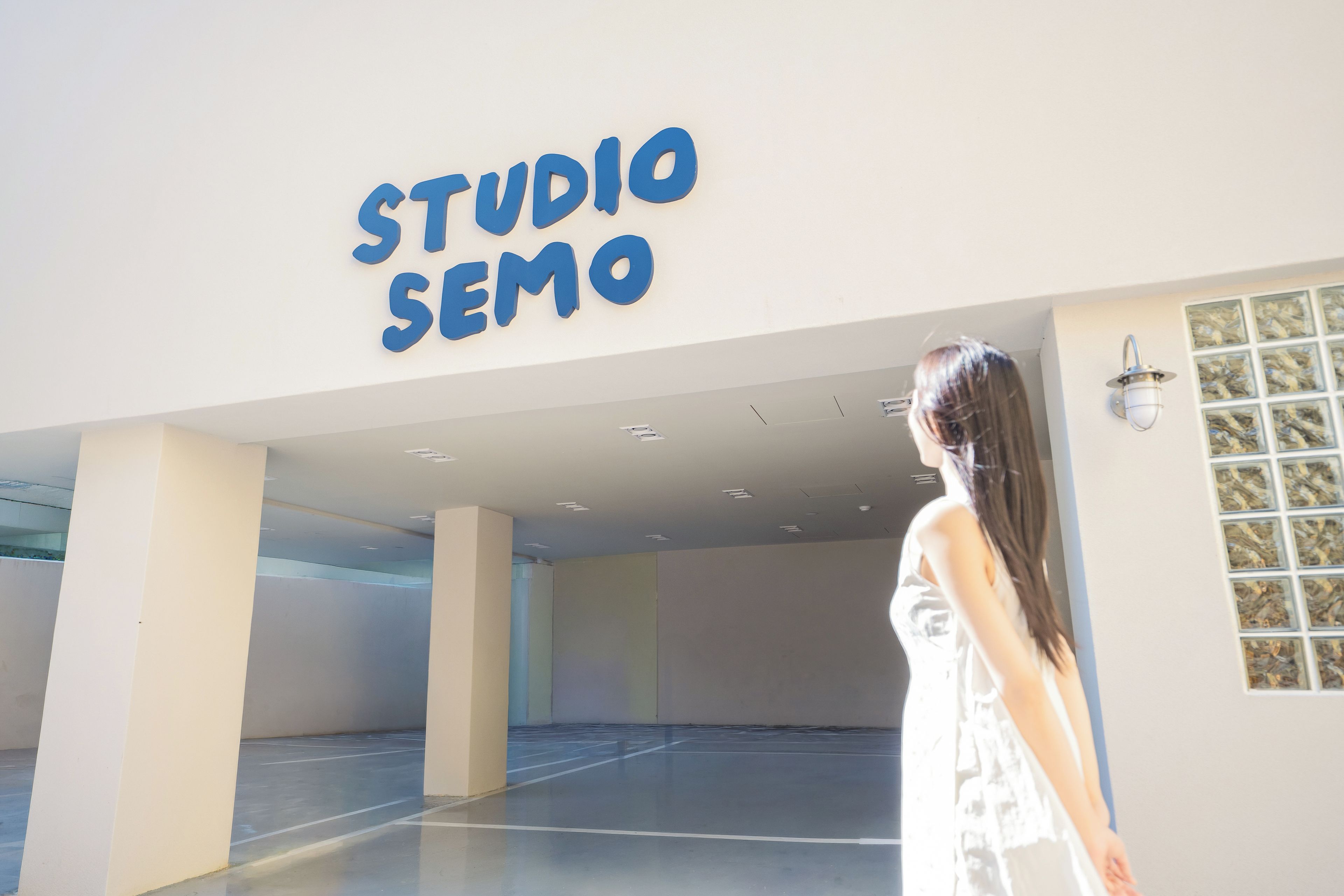 Una persona de pie en un espacio interior amplio y vacío, con un letrero que dice 'STUDIO SEMO'.