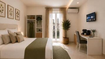 A hotel room with a bed, a desk, a chair, a TV, and a balcony with a view of buildings.