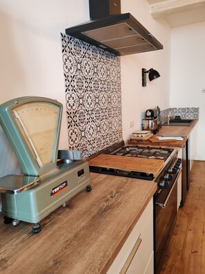 Une cuisine avec une balance ancienne, une cuisinière à gaz et un évier moderne.