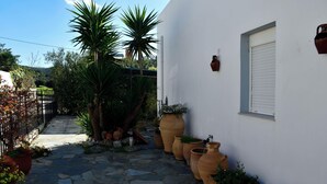A stone-paved courtyard with potted plants and a white wall. - Vrbo Property (Skouloufia)