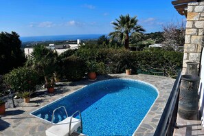 A swimming pool with a view of the sea, surrounded by greenery and stone architecture. - Vrbo Property (Skouloufia)