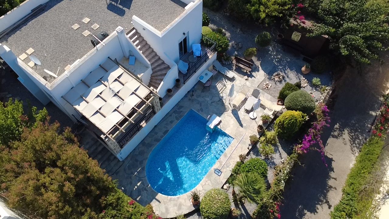 A modern two-story building with a swimming pool, outdoor seating, and a garden area.