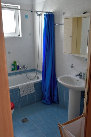 A bathroom with a bathtub, a shower, a sink, and a window. - Vrbo Property (Skouloufia)