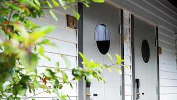A row of white motel rooms with numbered doors, each with a small window.