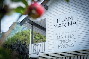 A sign for Flamm Marina Terrace Rooms with a heart-shaped decoration on the railing.