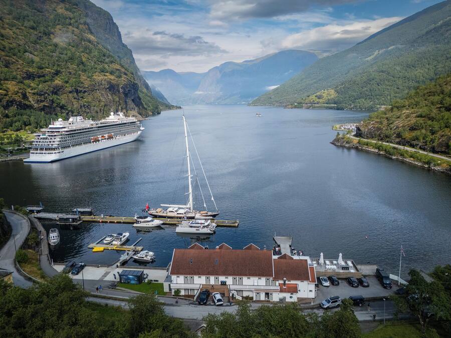 A cruise ship docked at a harbor with a mountainous backdrop.