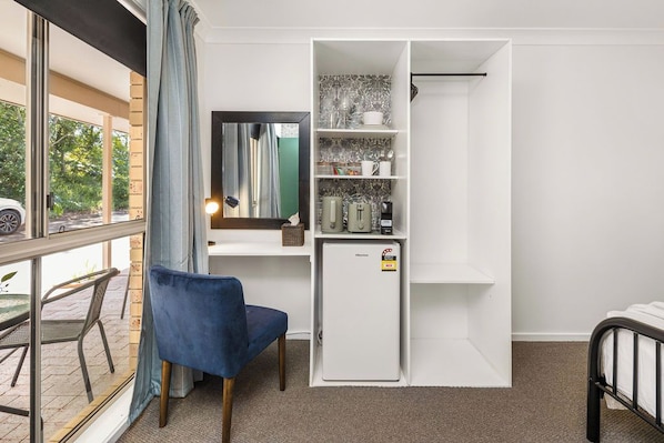 Habitación compacta con escritorio, silla y un refrigerador pequeño.