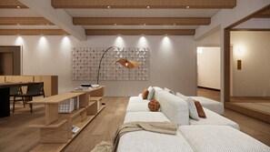 Ein modernes Hotelzimmer mit Holzboden, einer Sofagarnitur, einem Schreibtisch mit Büchern und einer Wandleuchte.