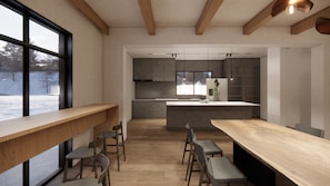 Una cocina moderna con una isla central, vigas de madera y un ventanal grande.
