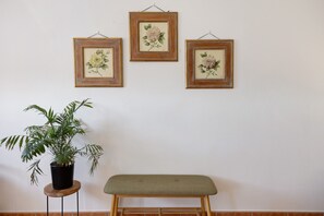 A room with a wooden bench, a potted plant, and three framed floral artworks on the wall. - Room 'Camera 7 - Economy Ampia' with Shared Pool, Wi-Fi and Air Conditioning (Cavaion Veronese)
