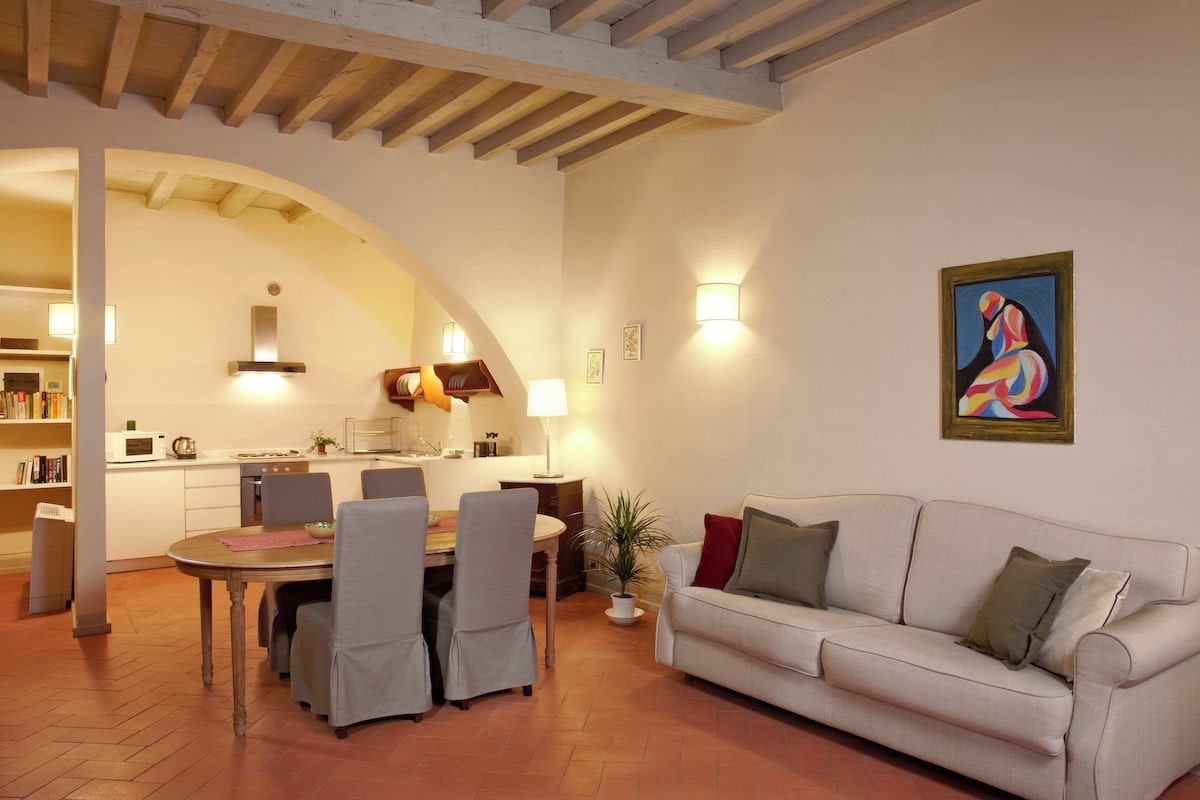 Una sala de estar con sofá, mesa de comedor, sillas y cocina al fondo.