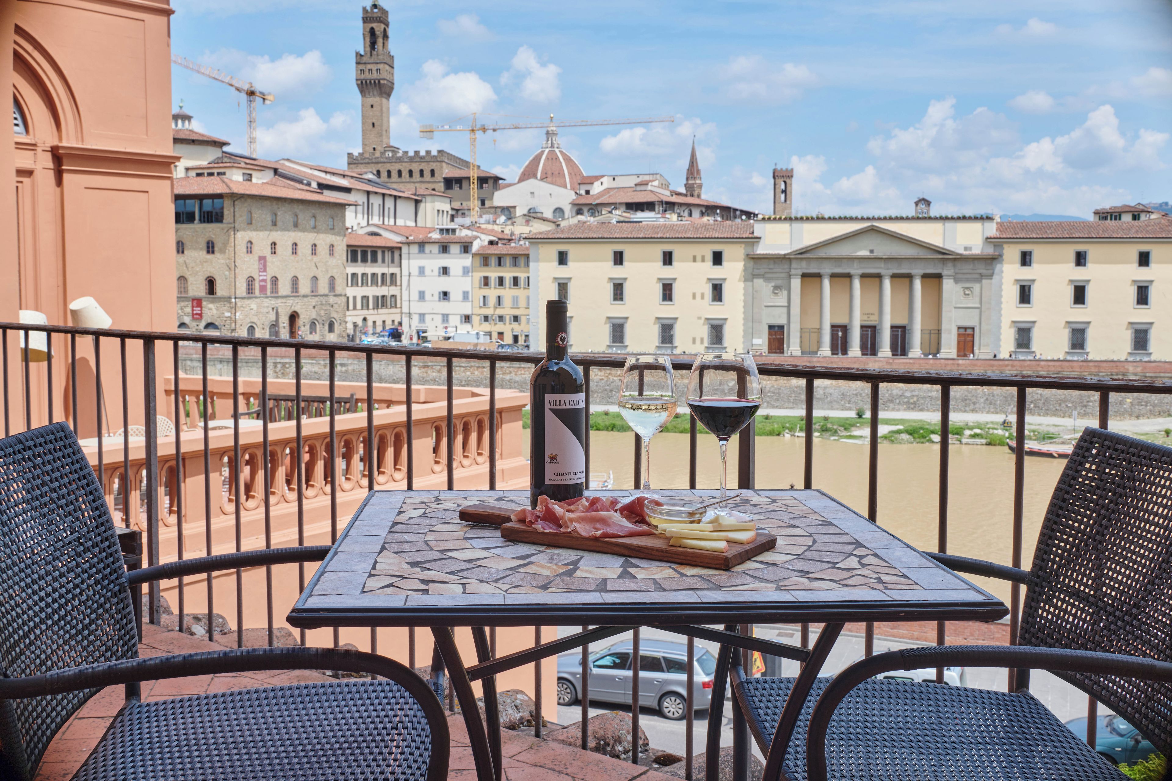 Una terraza con una mesa dispuesta para comer, con vistas a un casco antiguo con edificios y un río.