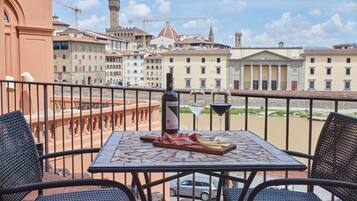 Una terraza con una mesa dispuesta para comer, con vistas a un casco antiguo con edificios y un río.