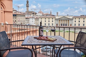 Una terraza con una mesa dispuesta para comer, con vistas a un casco antiguo con edificios y un río.