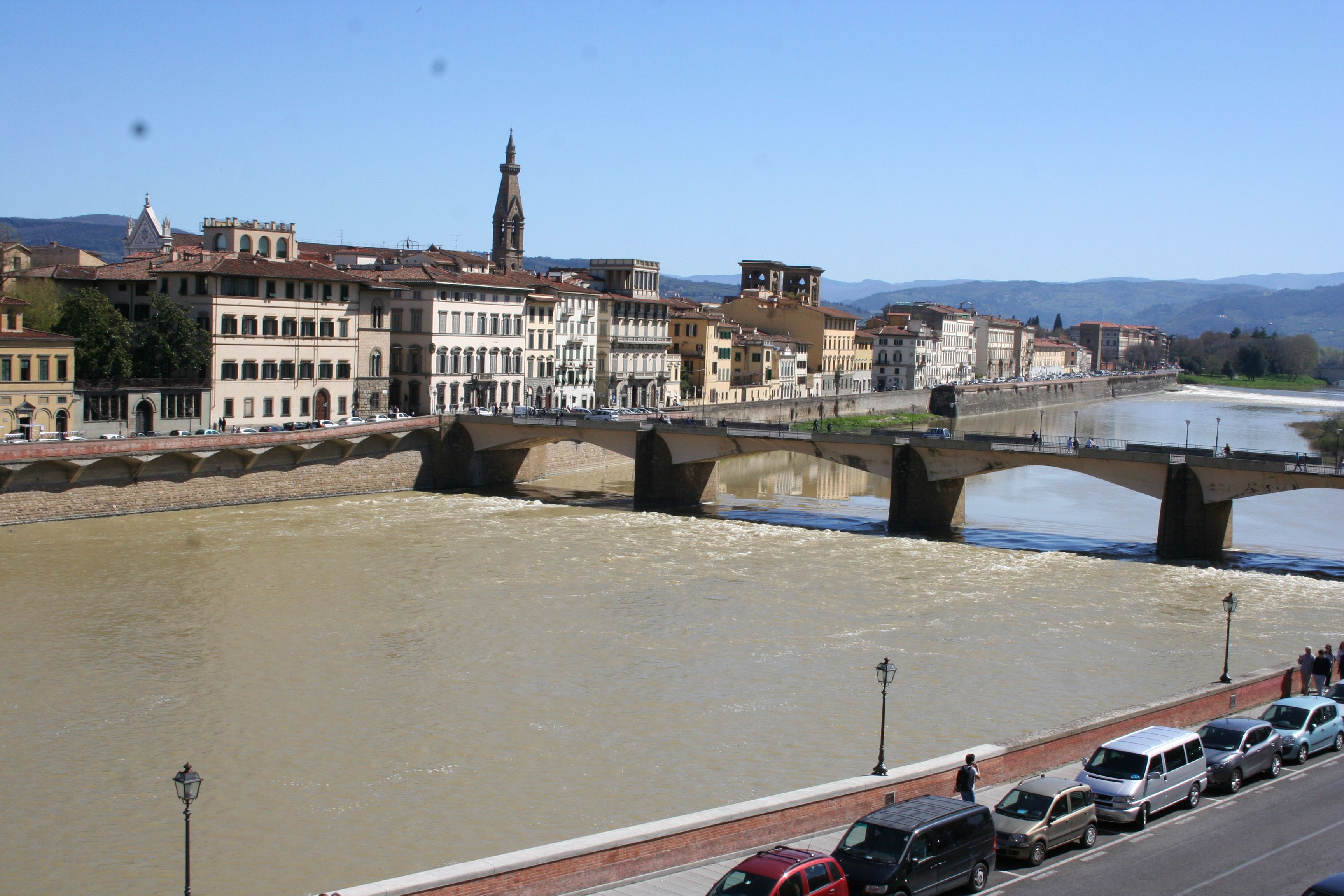 Un río con un puente, edificios y cielo despejado.