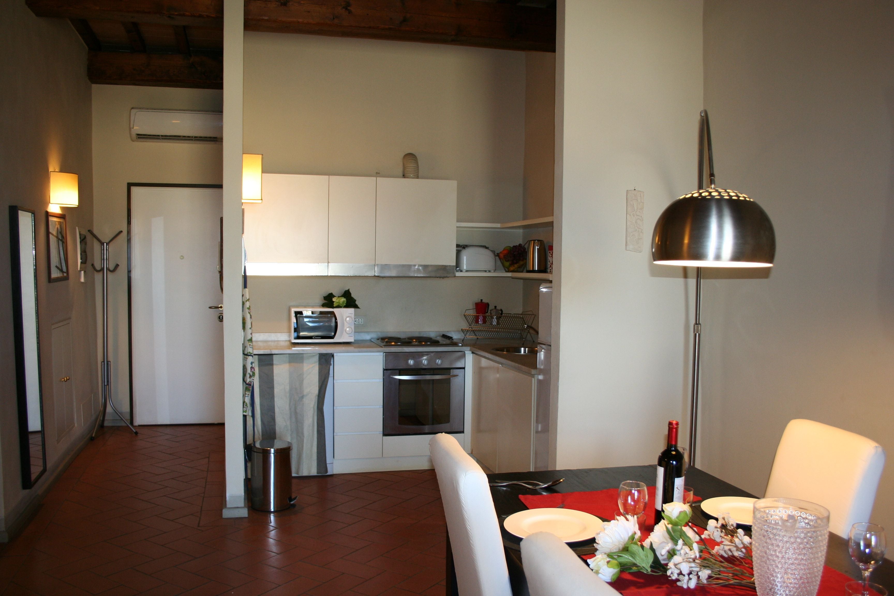 Cozinha compacta com área de jantar, incluindo mesa para dois, com garrafa de vinho e copos.