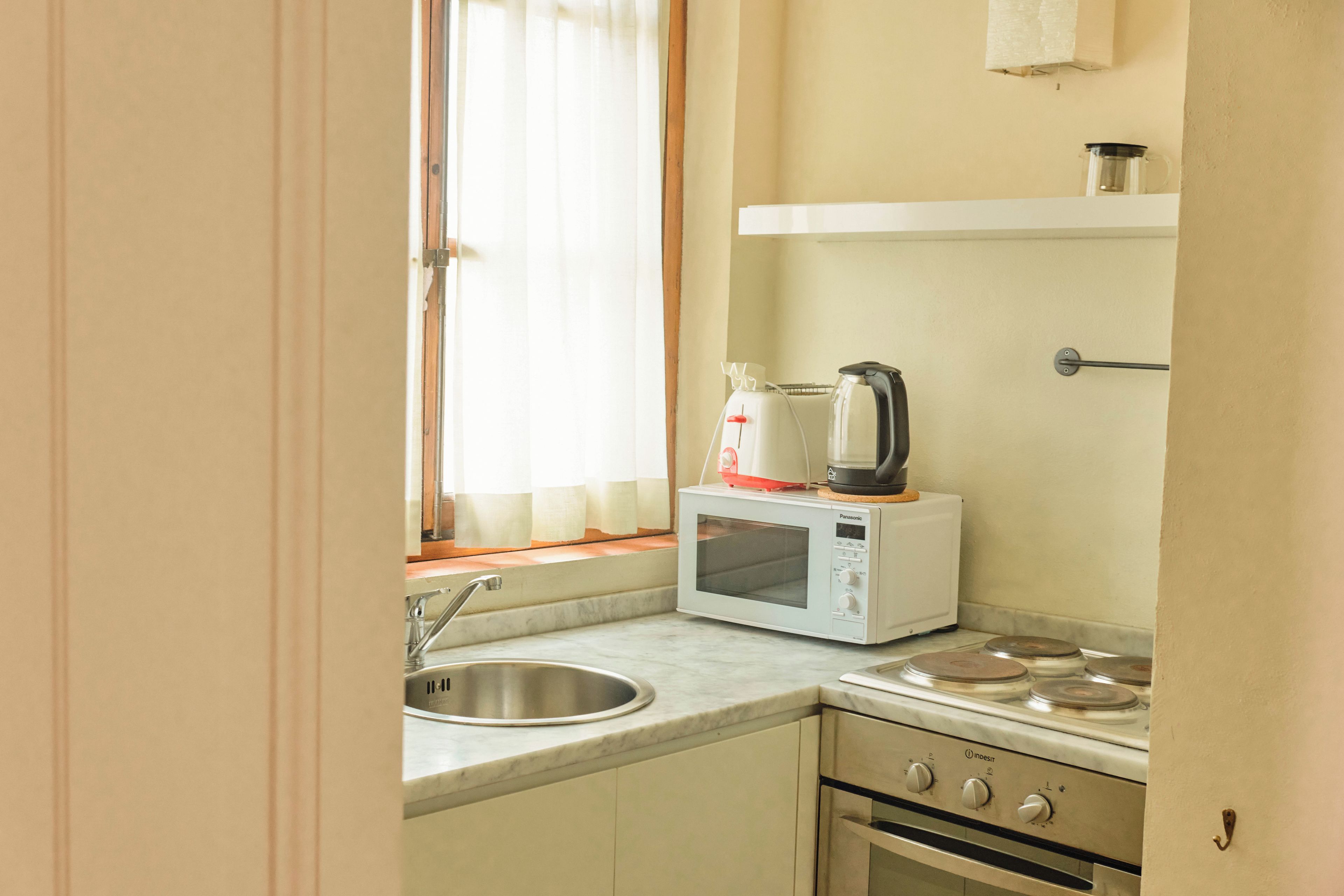 A compact kitchen with a sink, a microwave, and a stove.
