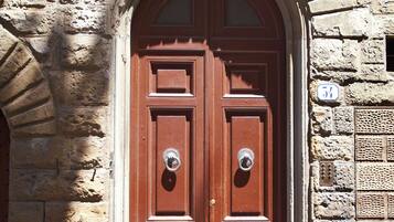 Una puerta doble de madera con un arco de piedra, un aldabón de metal y una placa con un número.