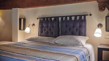 Una cama con colcha a rayas, dos lámparas de noche y un cabecero con cortina.