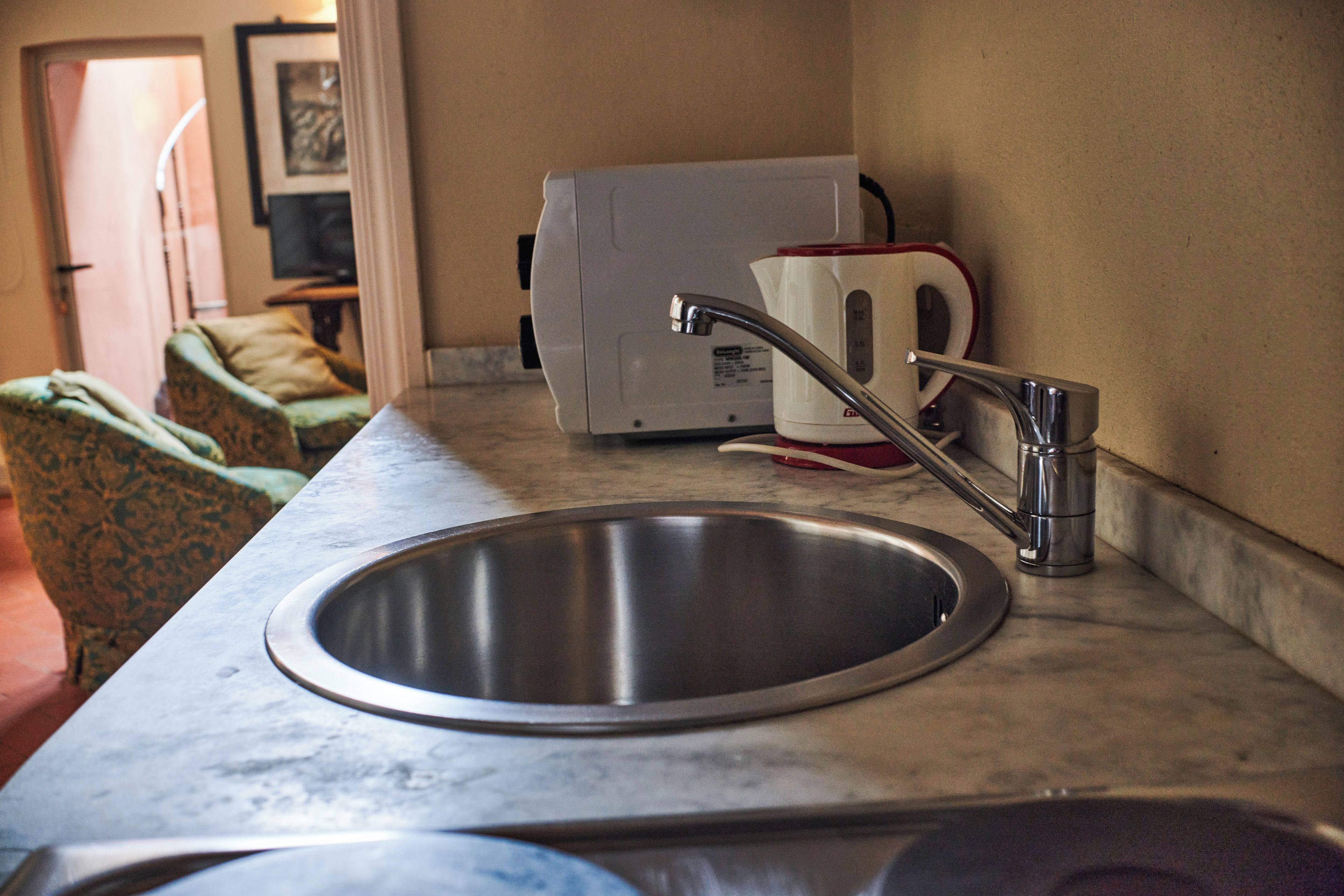 A kitchen with a stainless steel sink, a toaster, and a microwave on the countertop.