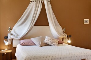 A bedroom with a canopy bed, bedside lamps, and a bedside table. - Room '8 - Economy Ampia' with Shared Pool, Wi-Fi and Air Conditioning (Cavaion Veronese)