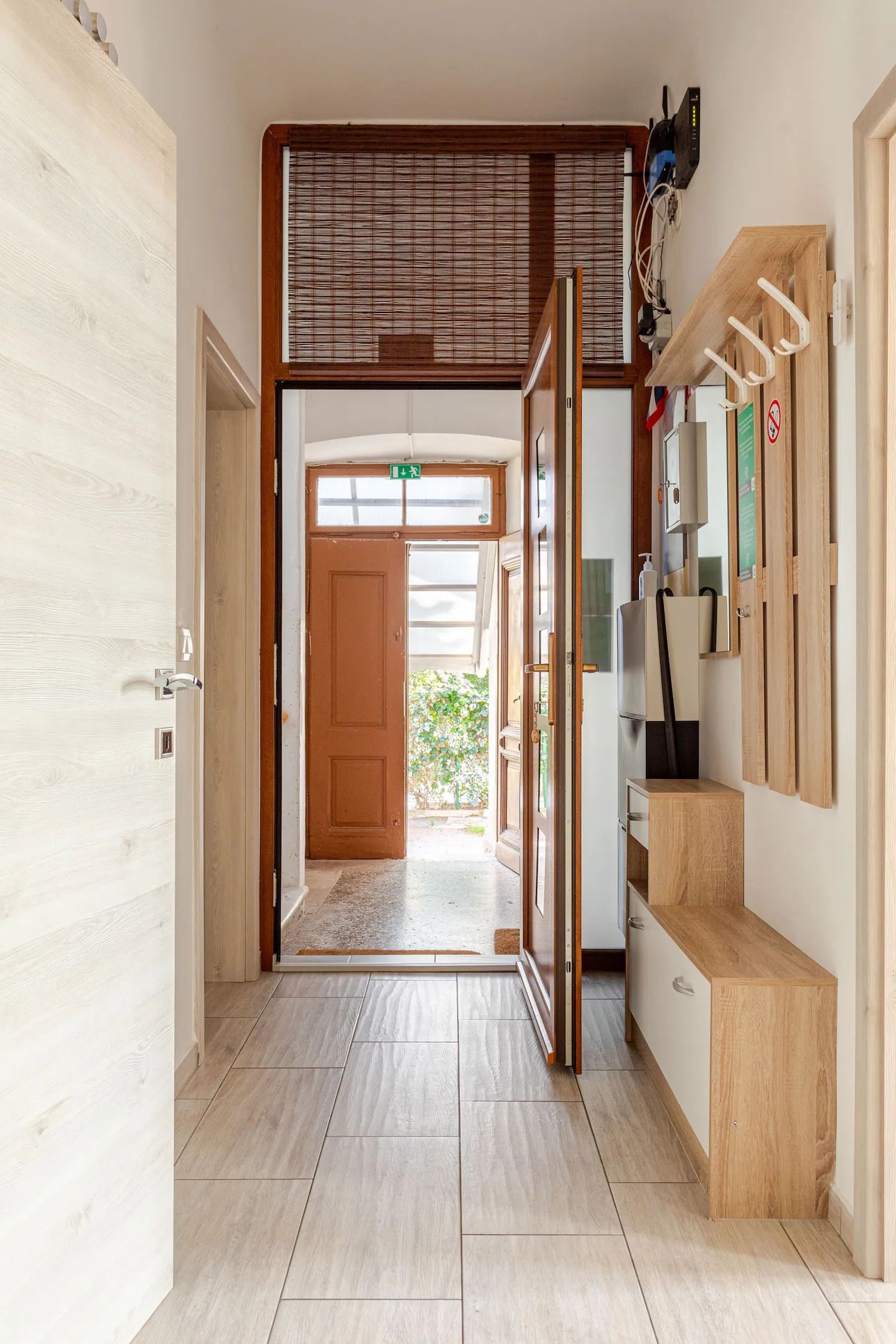 A hallway with a wooden door, a glass door leading outside, and a small wooden bench.