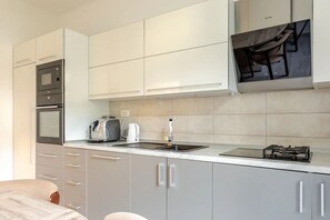 Une cuisine moderne dotée d’appareils électroménagers intégrés, d’un évier et d’une cuisinière à gaz.
