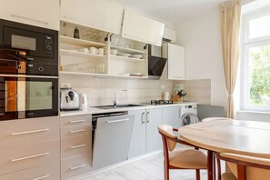 Cozinha moderna com eletrodomésticos embutidos, área de refeições com mesa de madeira e vista para o verde lá fora.